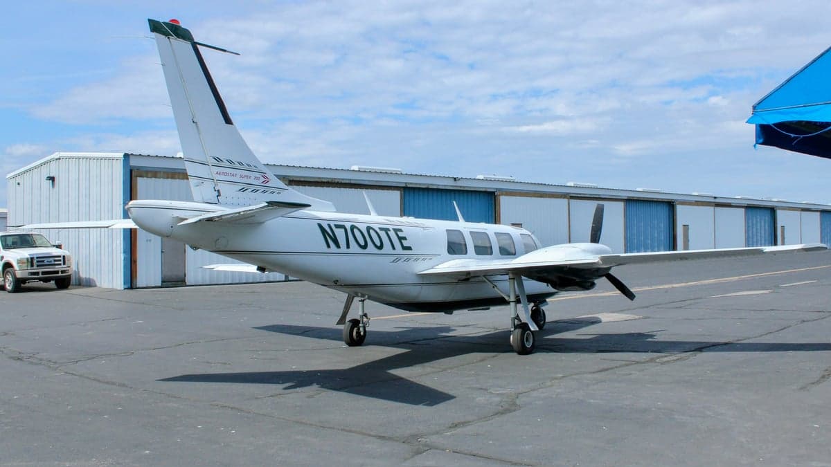 Aerostar Super 700 twin parked near a hangar.