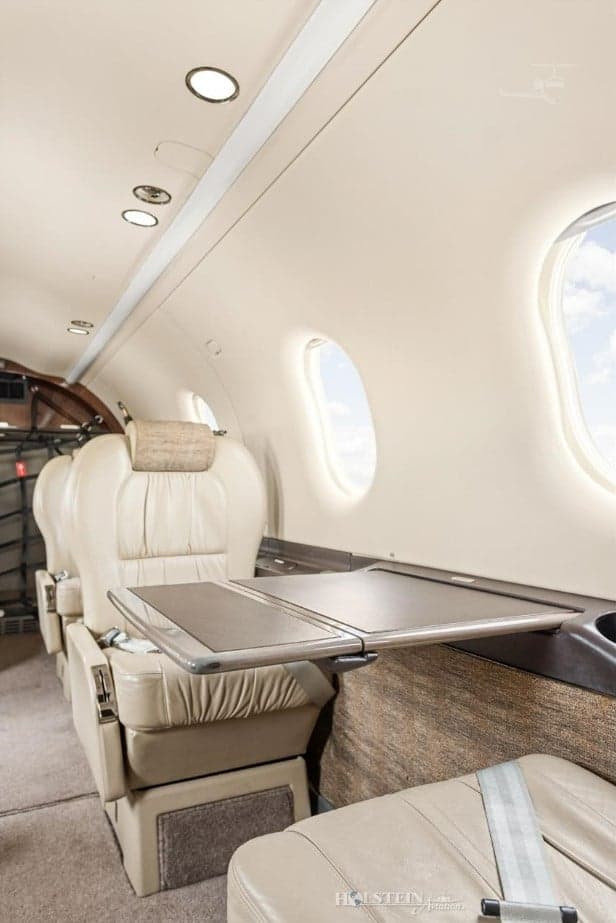 Side view of the Pilatus PC-12 cabin with leather seats and a fold-down table.