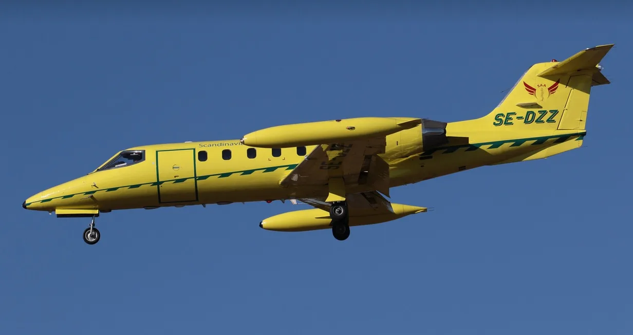 Yellow Scandinavian Air Ambulance jet in flight.