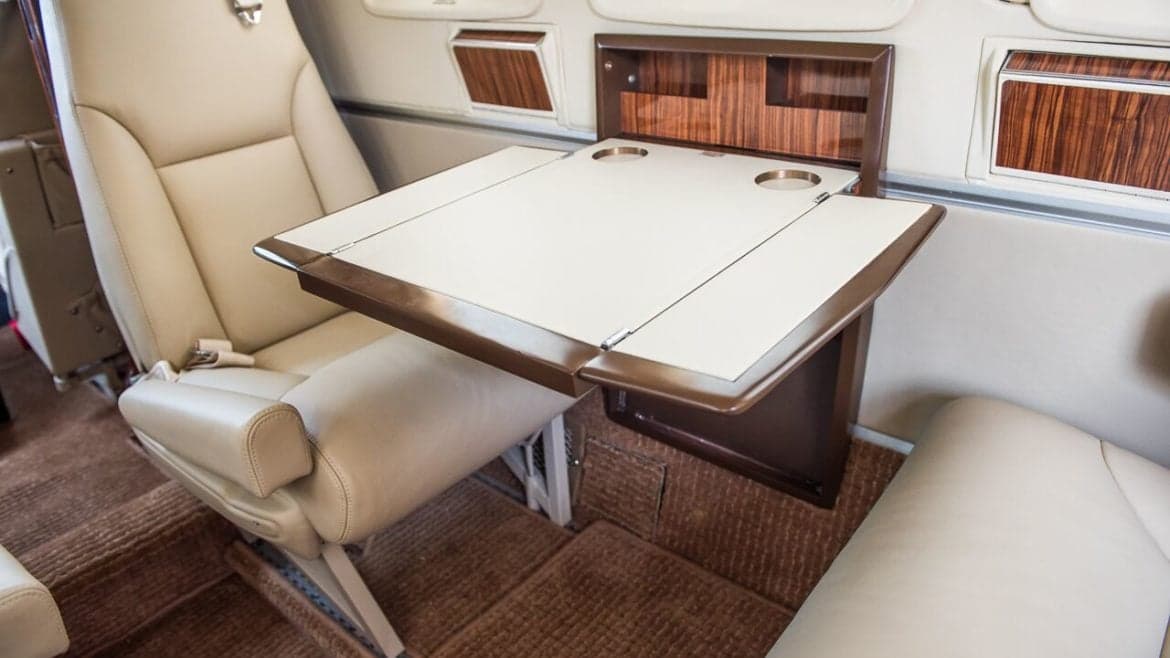 Aircraft interior with leather seats and a folding table.