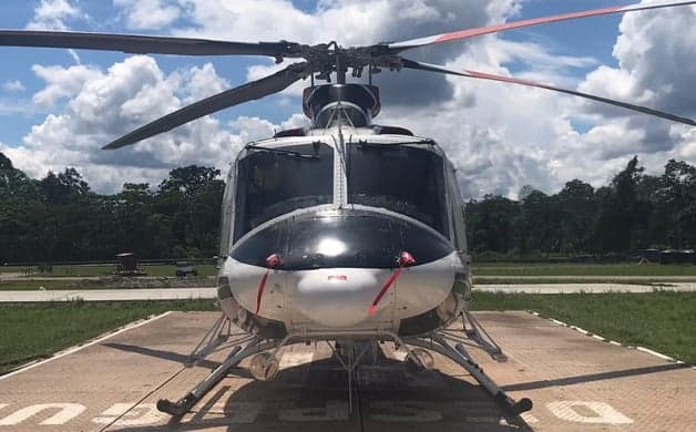Side view of a red and white Bell 212 helicopter on a helipad.