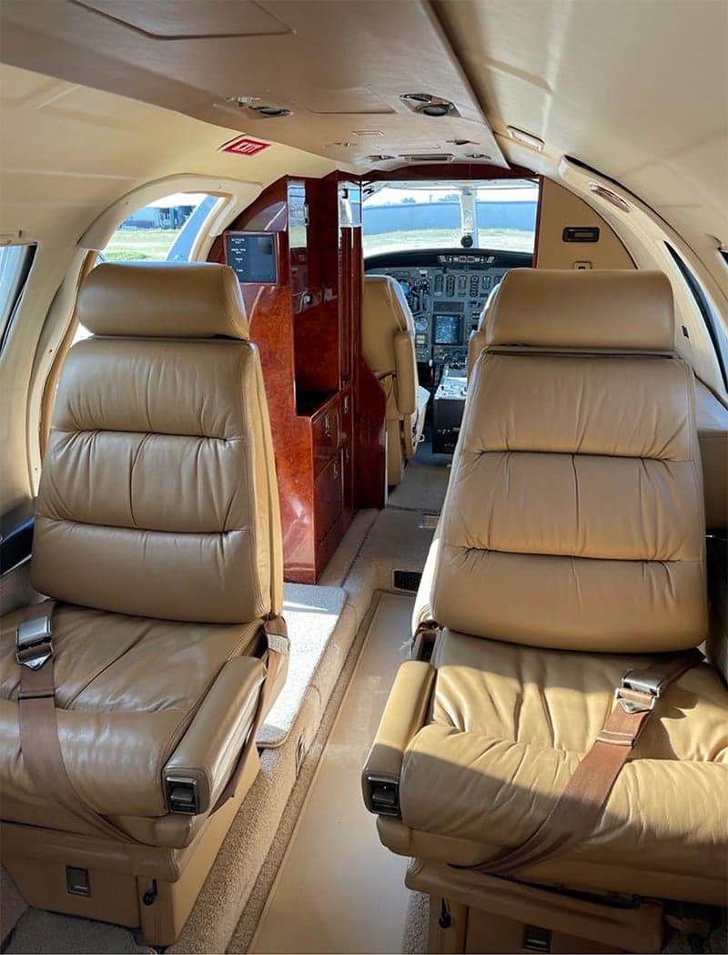 The interior of a Cessna Citation CJ3 features tan leather seats and a view of the cockpit.