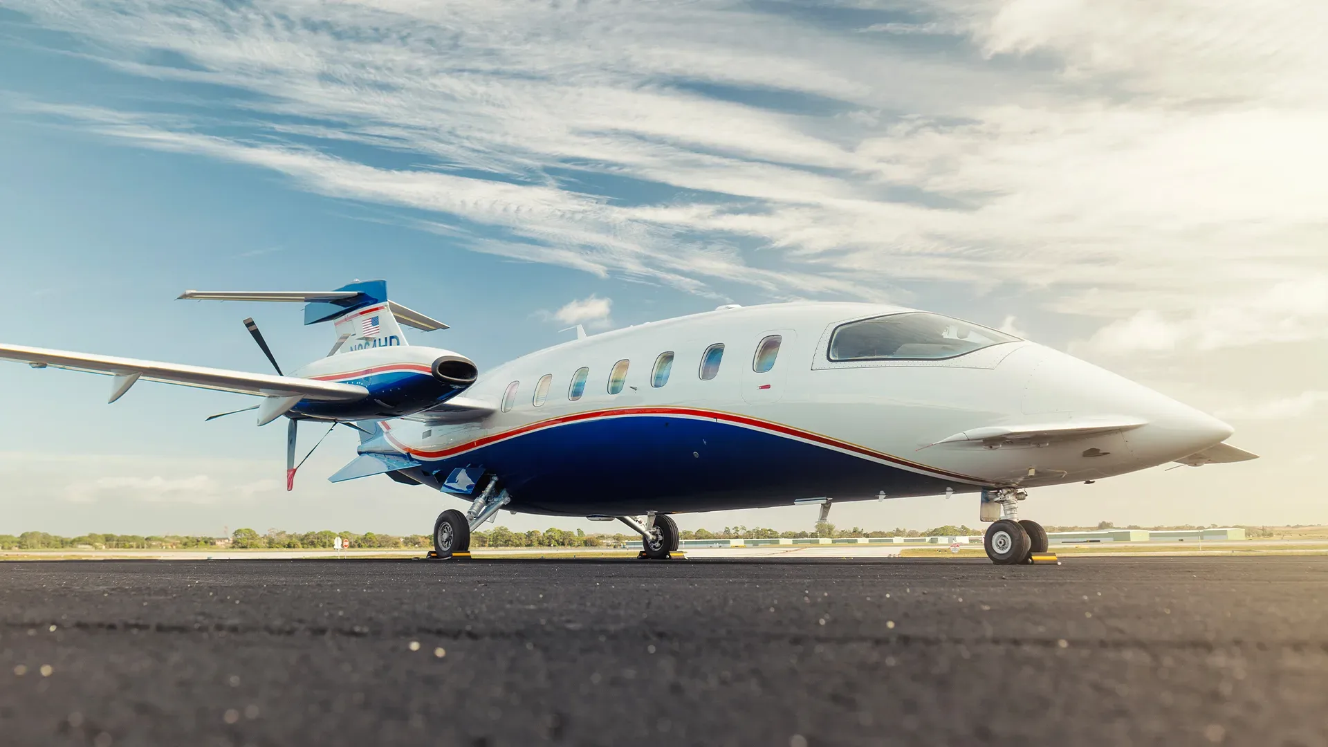 A Piaggio Avanti EVO aircraft is parked on the tarmac with a blue and white paint scheme.