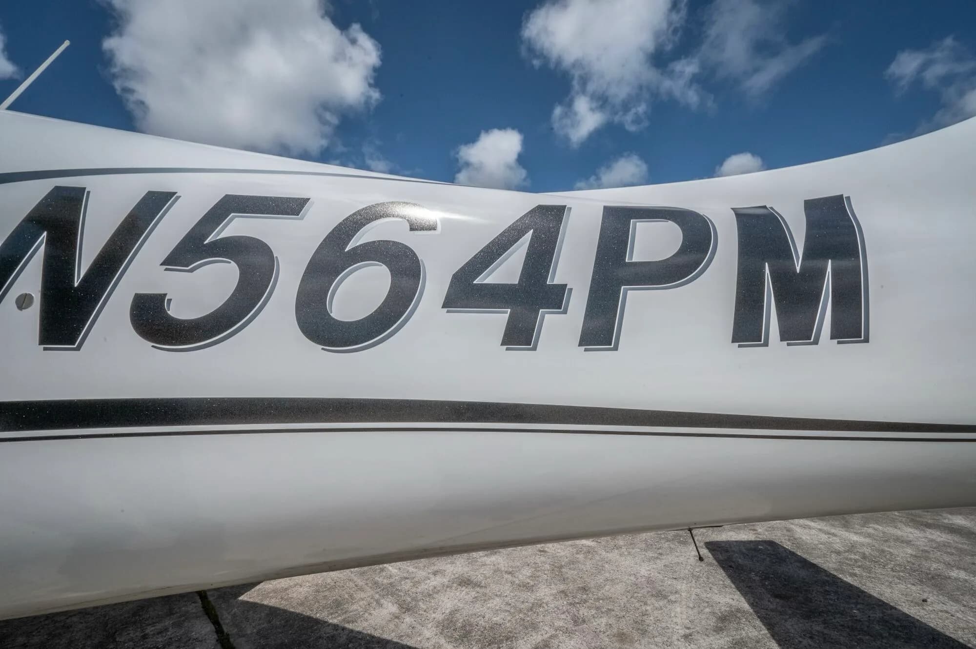 A close-up of the N564PM registration number on the white fuselage of the Cirrus SR22 GTS aircraft.