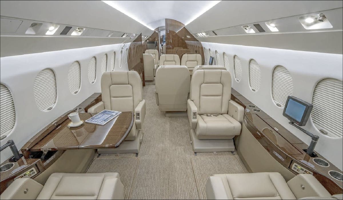 Wide view of the interior cabin of a jet with leather seats and wood trim.