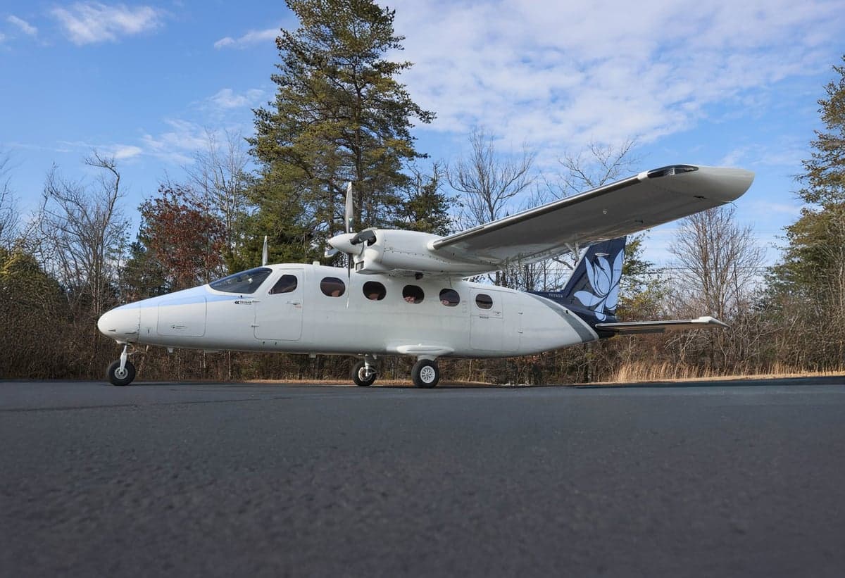Side view of a white and blue Tecnam P2012 Traveller aircraft on the ground.