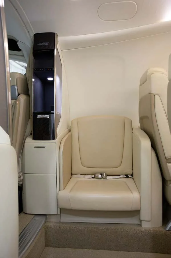 A single light-colored leather cabin seat next to a dark and light-colored storage unit.