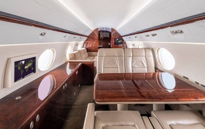 The interior cabin of a Gulfstream G450 aircraft with tables and seats.