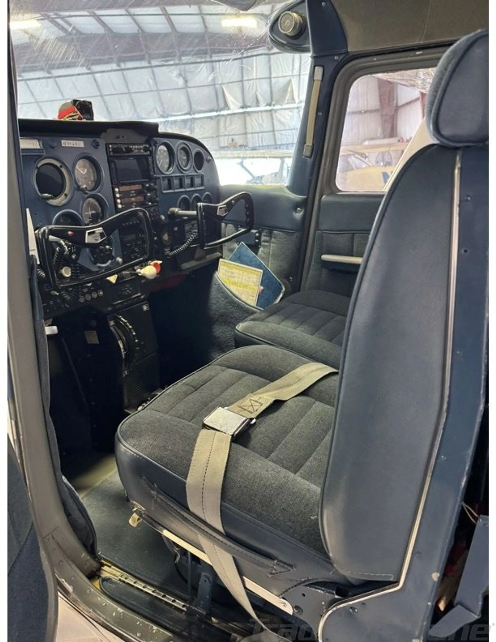 The interior cabin of a Cessna 172, showing blue fabric seats and part of the instrument panel.