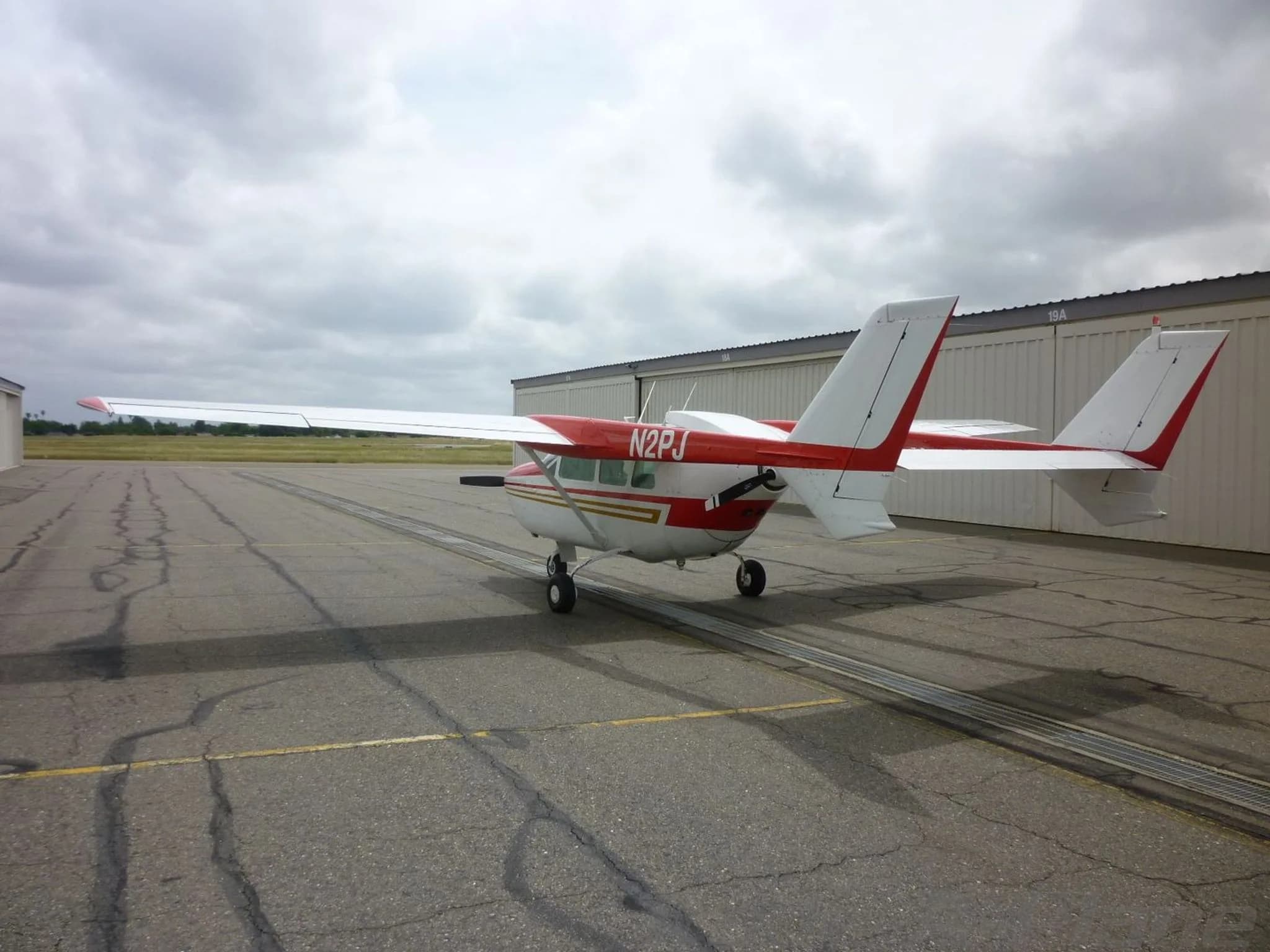 A three-quarter rear view of the white and red Cessna Skymaster N2PJ on an asphalt apron.