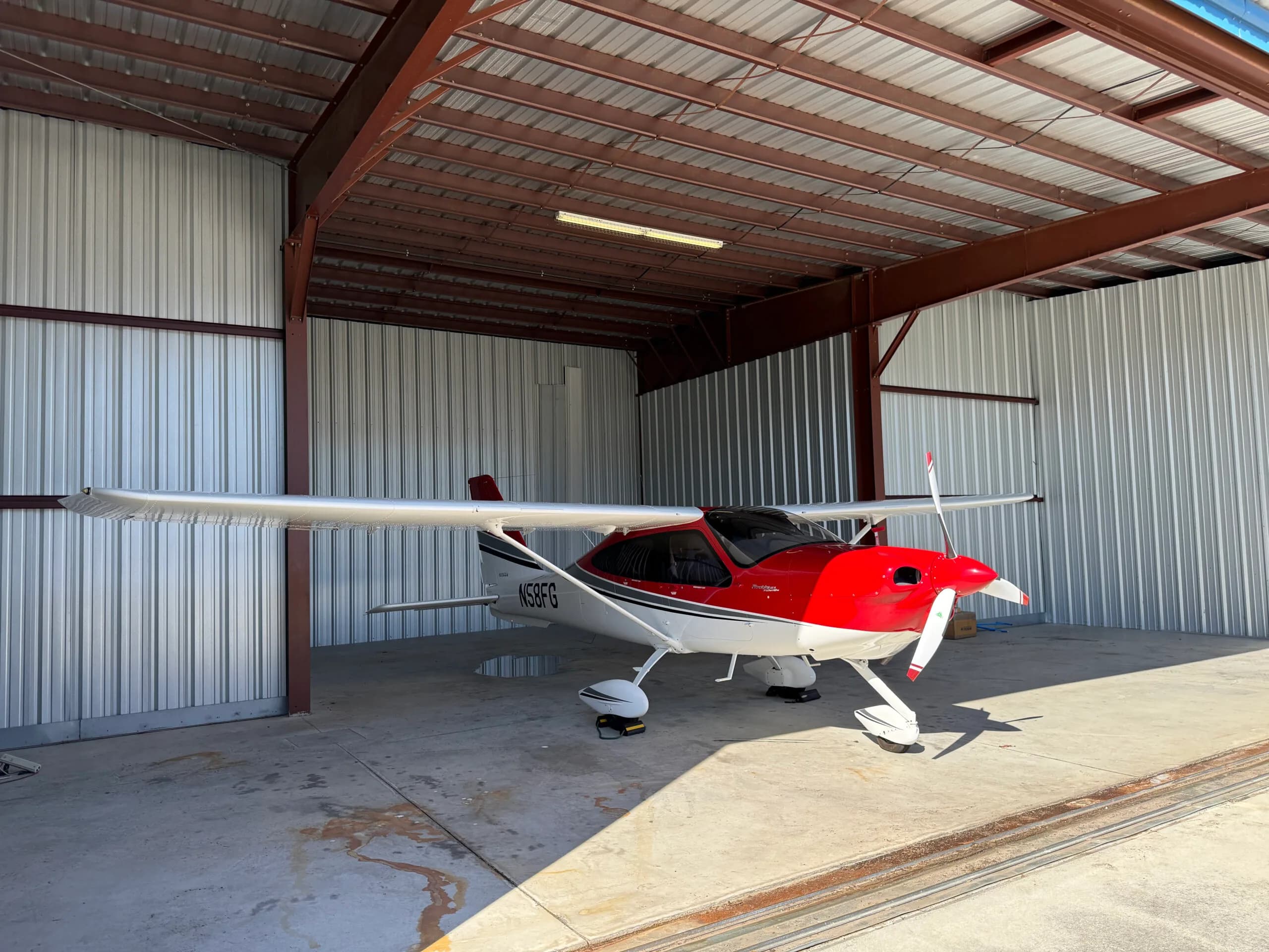 Tecnam P2010 aircraft N58FG parked in a hangar with a red and white paint scheme.