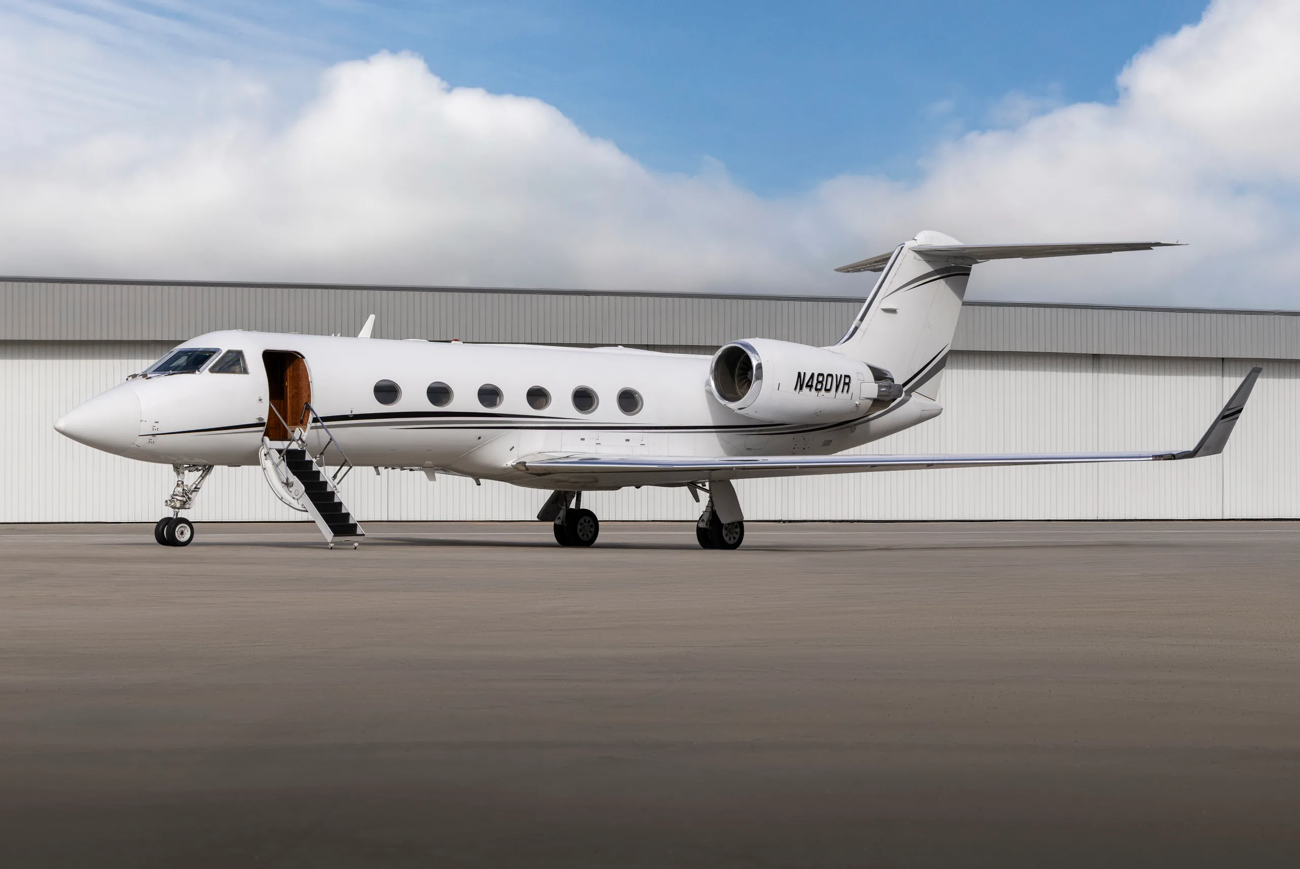 A white Gulfstream G550 business jet with registration N480VR parked on the tarmac with its main door open.