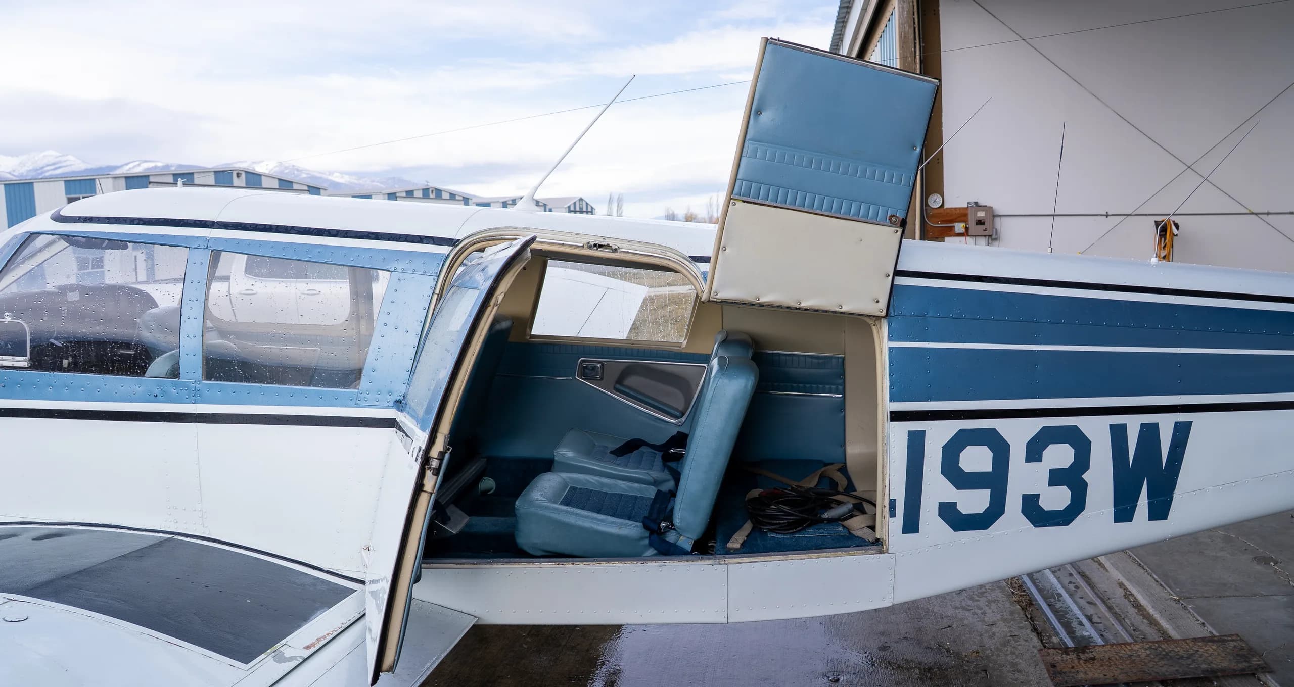 Open door of the aircraft revealing blue interior seats and part of the cockpit.