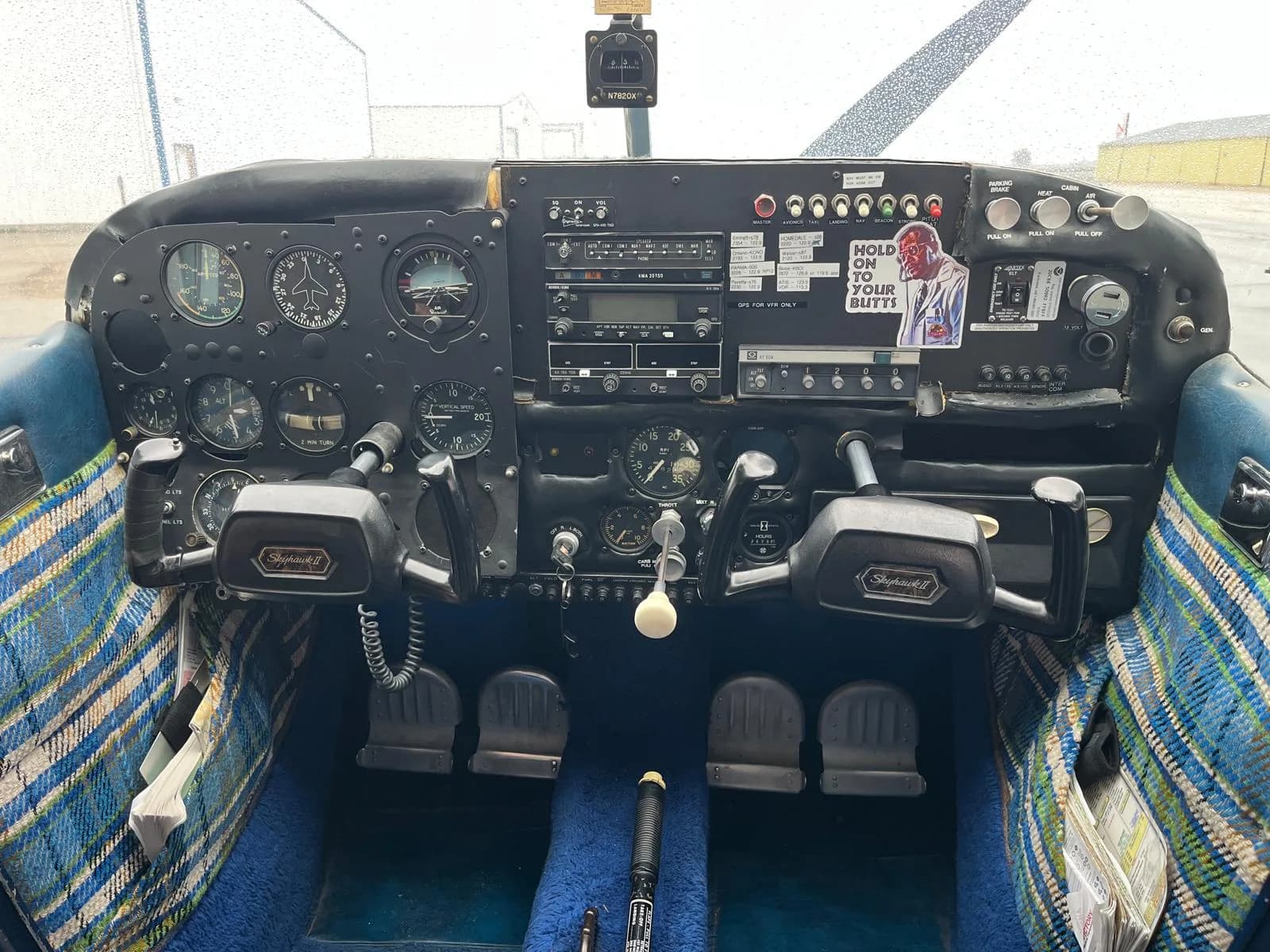 The cockpit of a Cessna 172 Skyhawk, showing the instrument panel, yokes, and blue carpet.