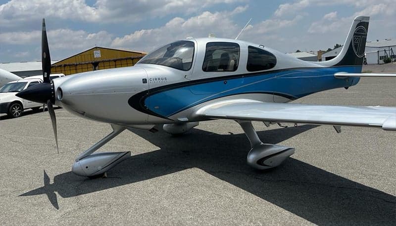 Side view of a silver and blue Cirrus SR22 on the tarmac.