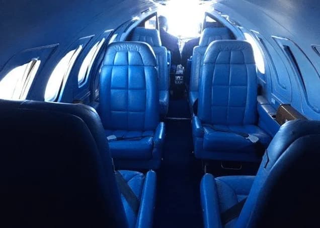 A wider view of the aircraft's blue leather cabin interior, showing multiple rows of seats.