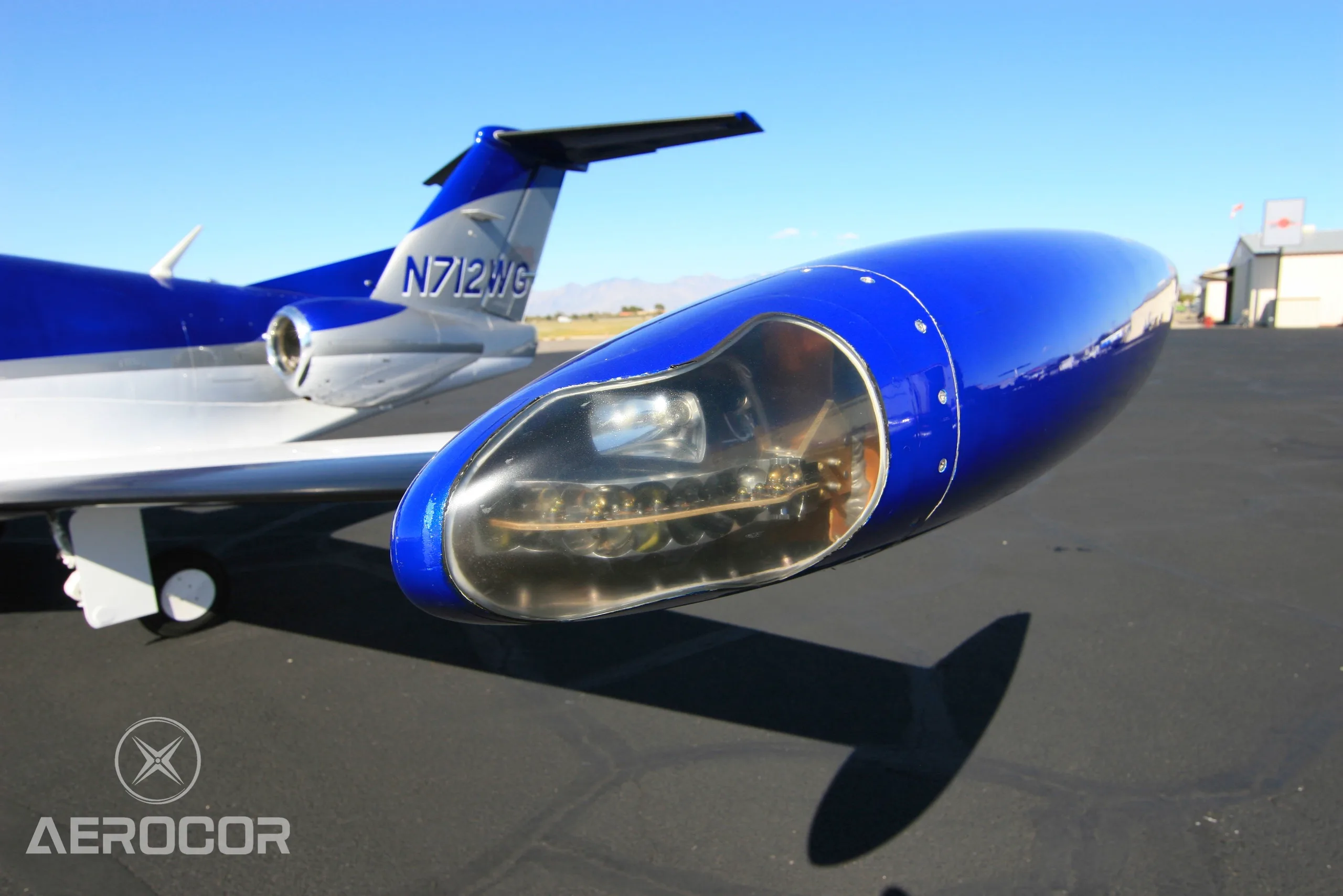 A close-up view of the wingtip and tail section of the blue and white Eclipse 500/550 jet, N712WG.