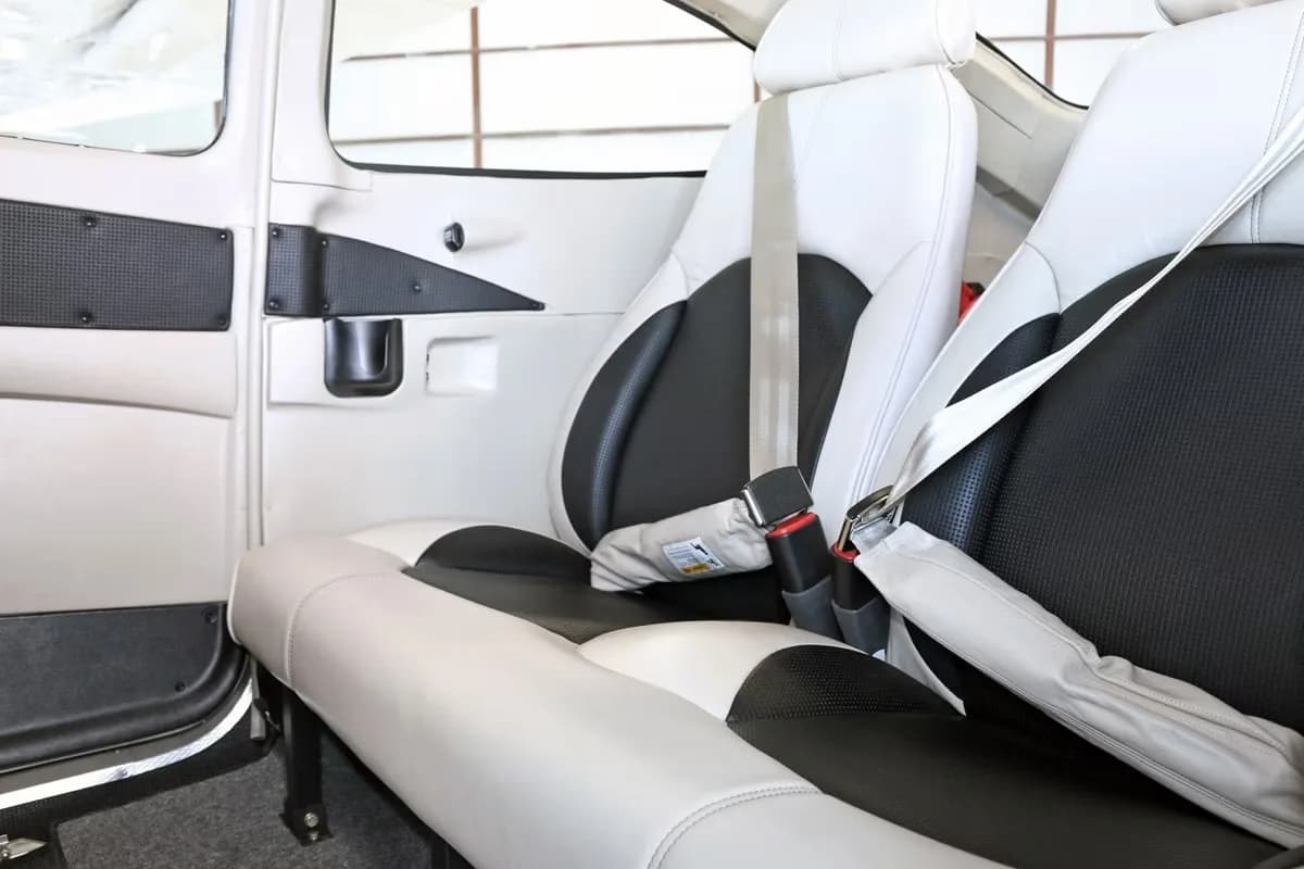 The interior cabin of the Cessna Skylane, showing two-tone white and black seats with seatbelts.