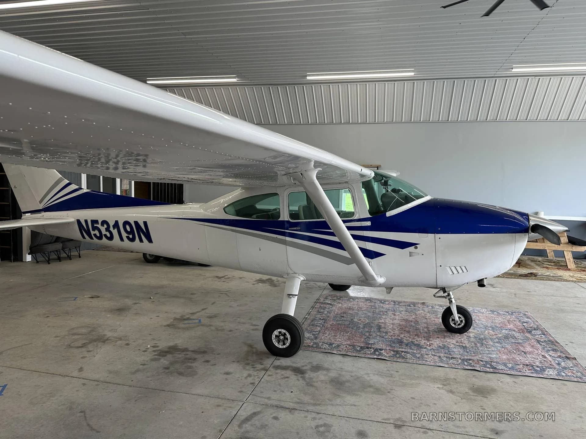 A white and blue Cessna aircraft with registration N5319N is parked inside a hangar, viewed from the side.