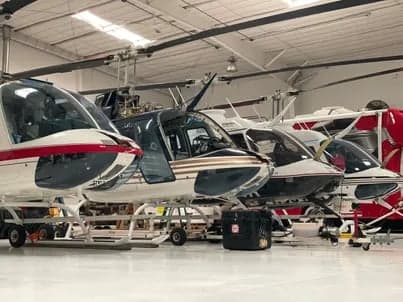 Several MD 500 helicopters are parked in a hangar.