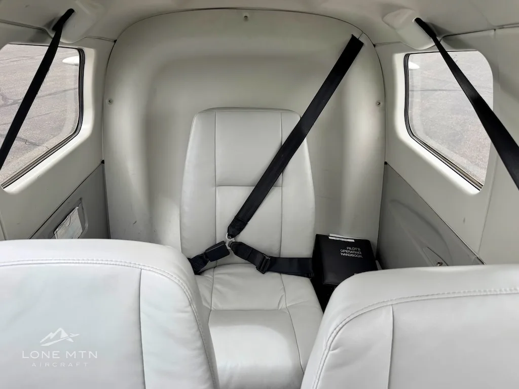 A view of the light gray rear cabin seat with a black seatbelt, seen from between the front seats.