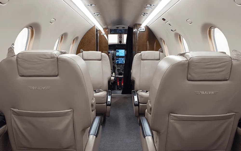 The beige leather interior cabin of a Pilatus PC-12 NG, looking forward towards the cockpit.