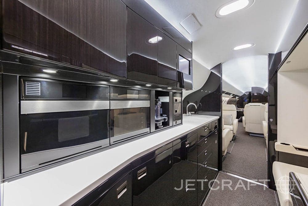View of the aircraft galley with dark wood cabinets and stainless steel appliances.