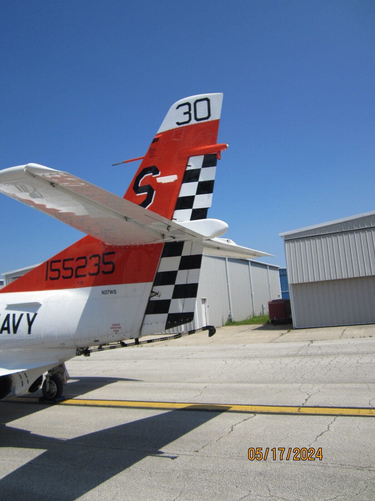 Rear view of the T-2B Buckeye aircraft's tail section and hangar in the background.