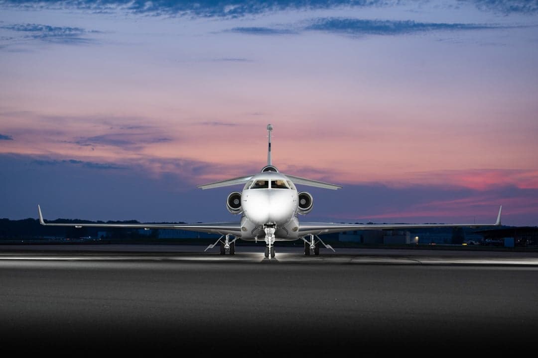 Front view of a white aircraft on the tarmac at dusk.