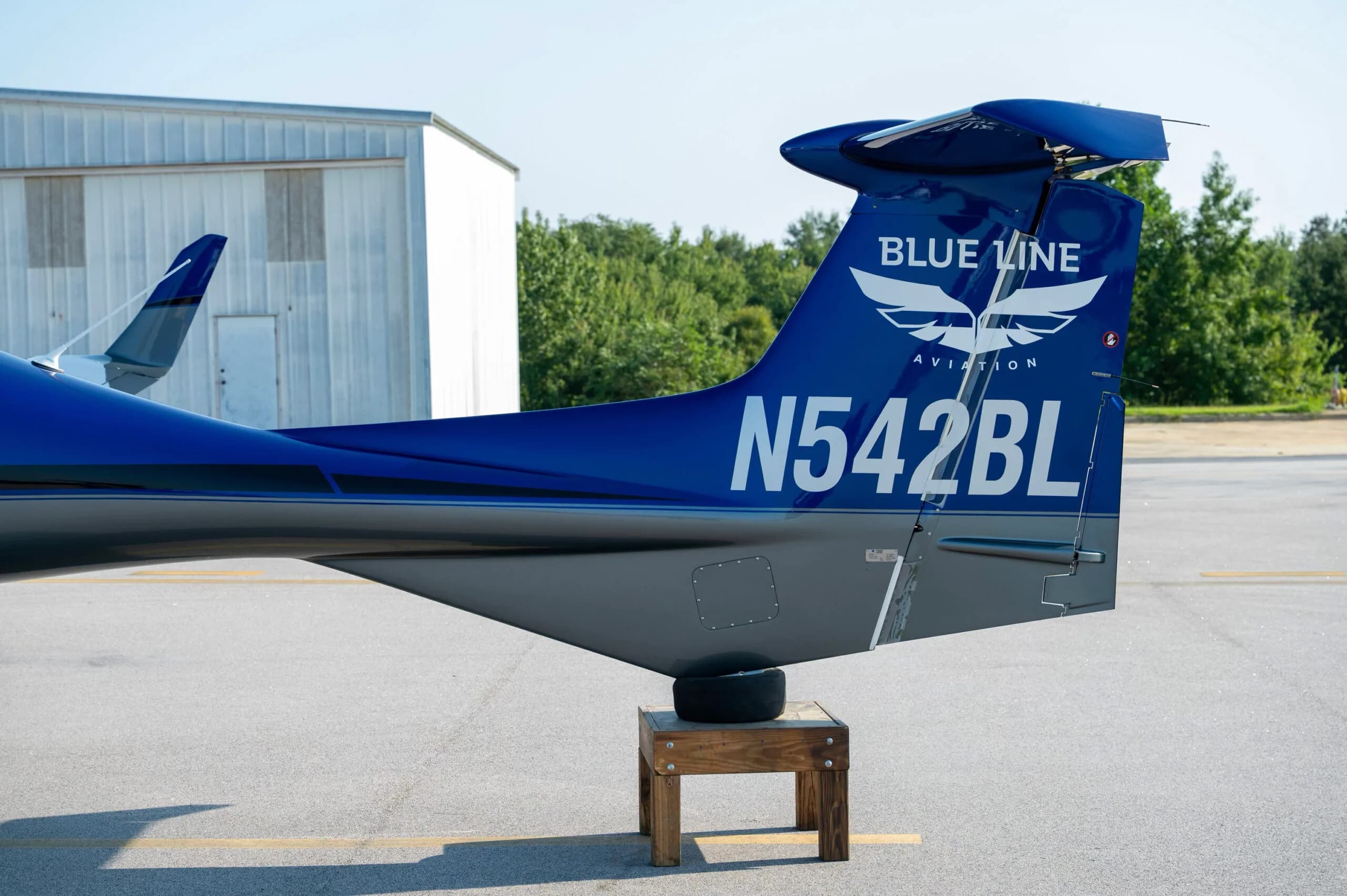 Close-up of the tail of a blue and grey Diamond DA42 aircraft showing the N-number and "Blue Line Aviation" logo.