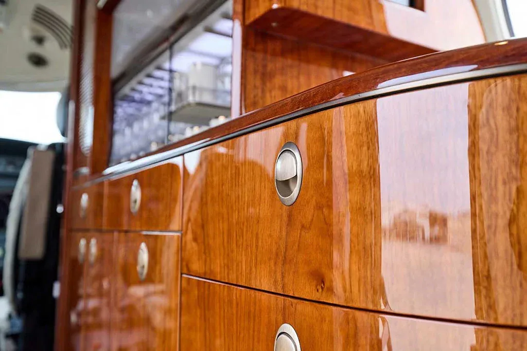 A detailed close-up of the highly polished wooden cabinetry and silver hardware inside the aircraft cabin.