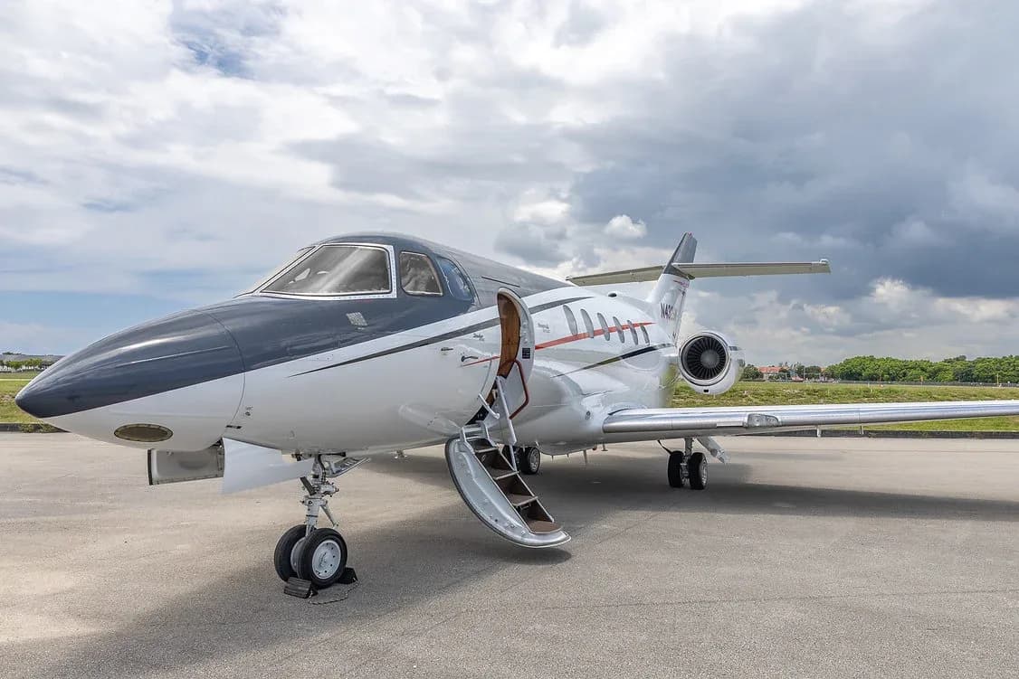 A white and black business jet, registration N432SM, with its passenger door open and stairs extended, parked on an airfield.