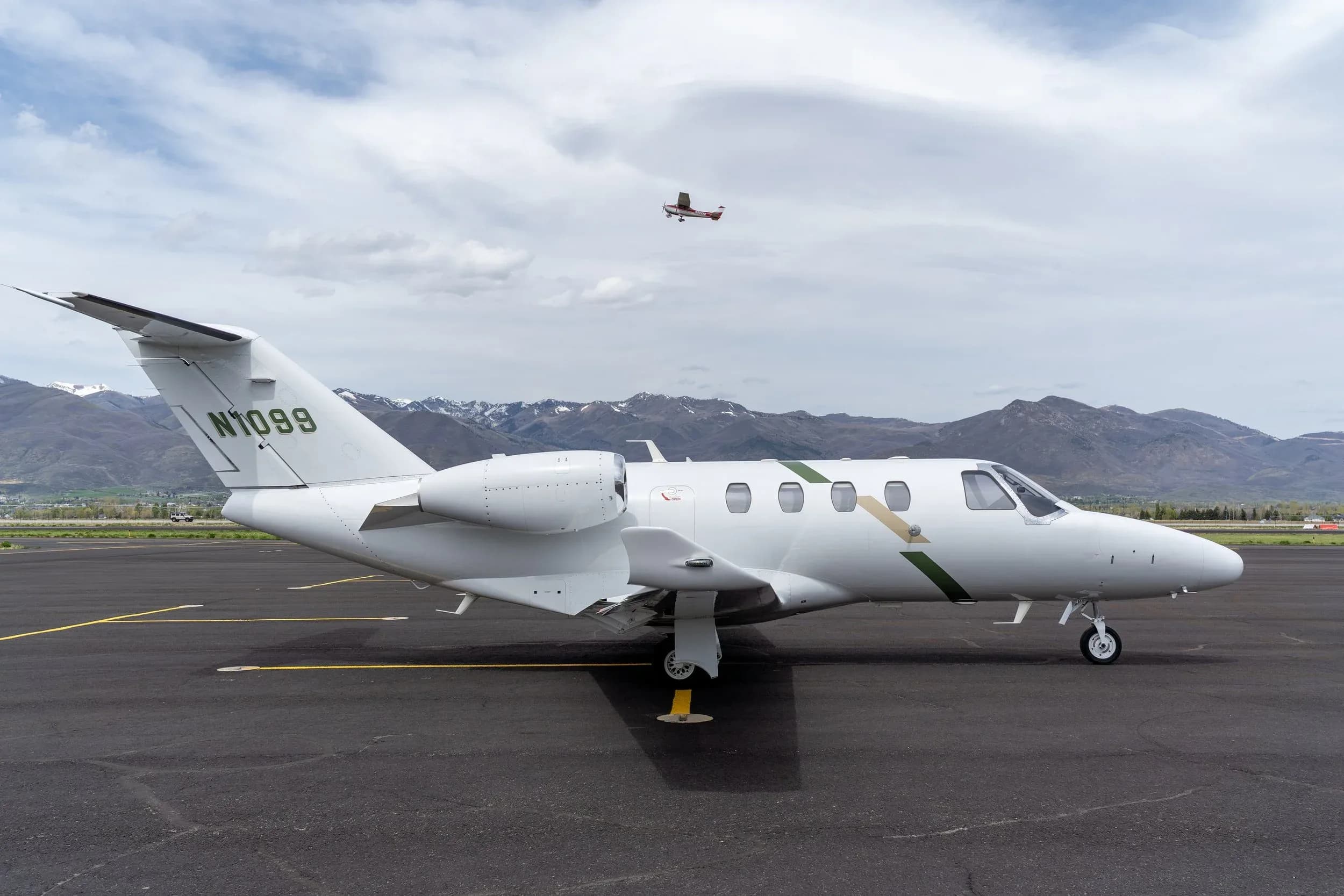 Cessna Citation CJ3+ aircraft N1099 on the tarmac with mountains in the background.