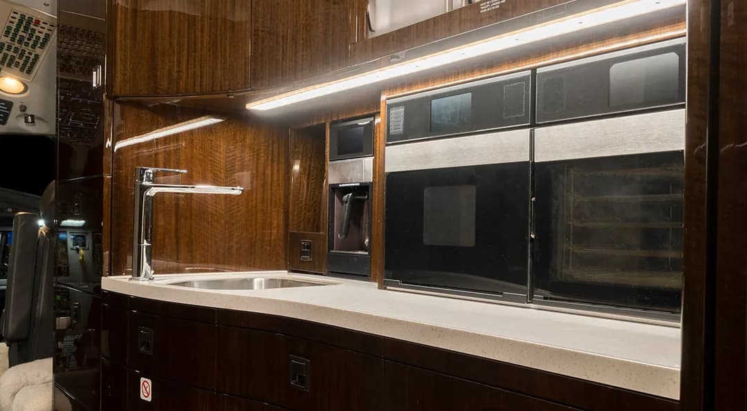 The aircraft interior features a galley with a sink, microwave, and oven.