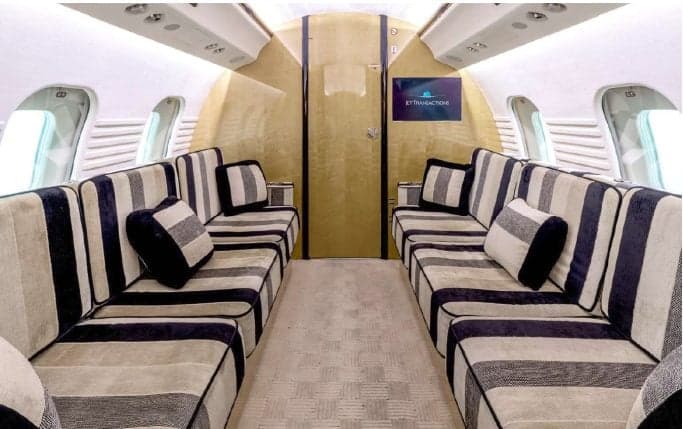 A view of the aircraft's interior with cream-colored leather seats and wooden tables.