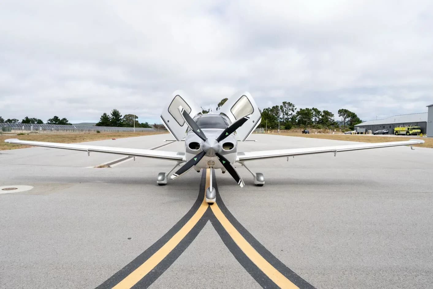 Front view of a white and grey Cirrus SR22 G3 Turbo aircraft, N788SR, with its doors open, parked on an airfield.