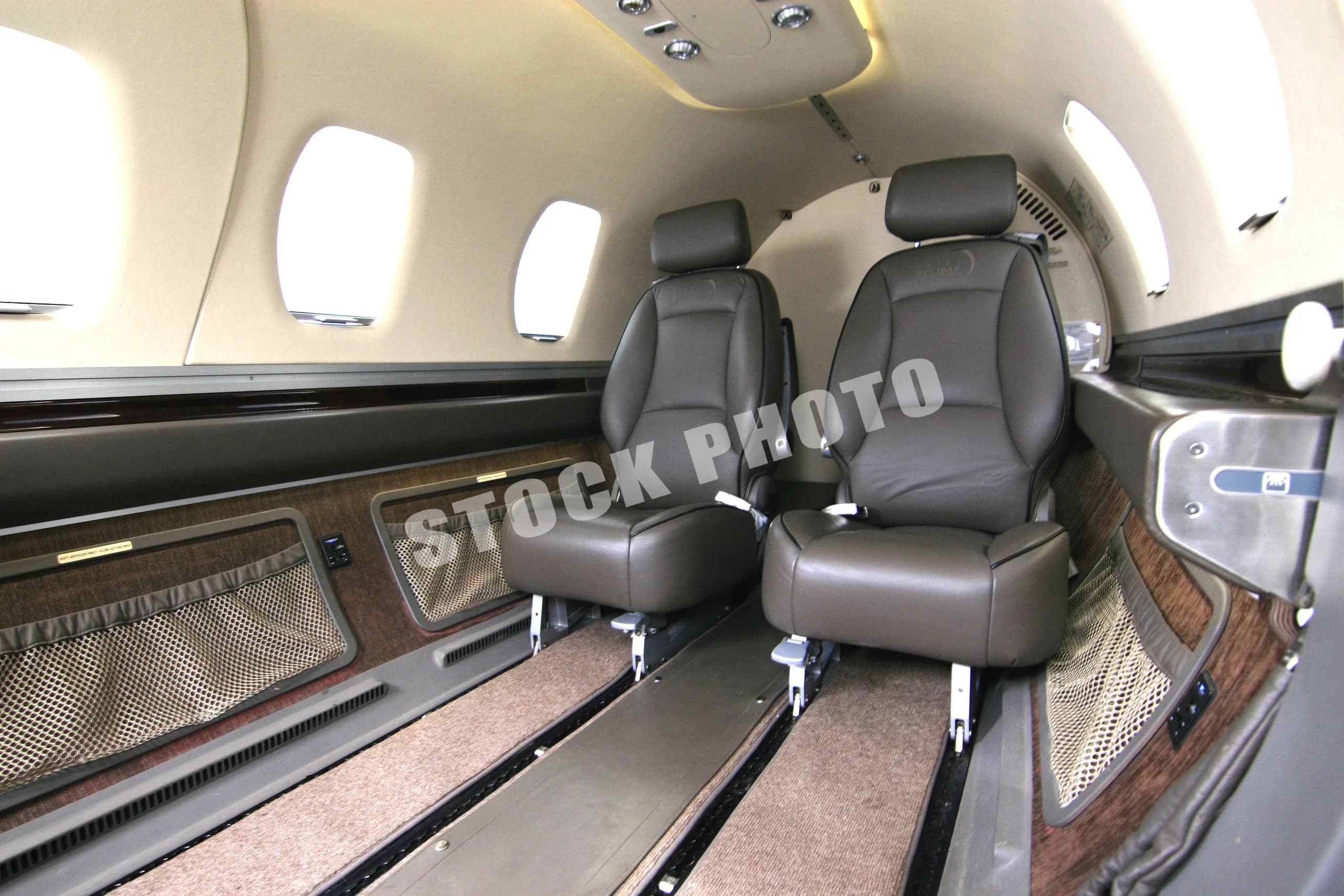 An angled view of the Eclipse 500 cabin interior, showing two brown leather passenger seats and side panels.