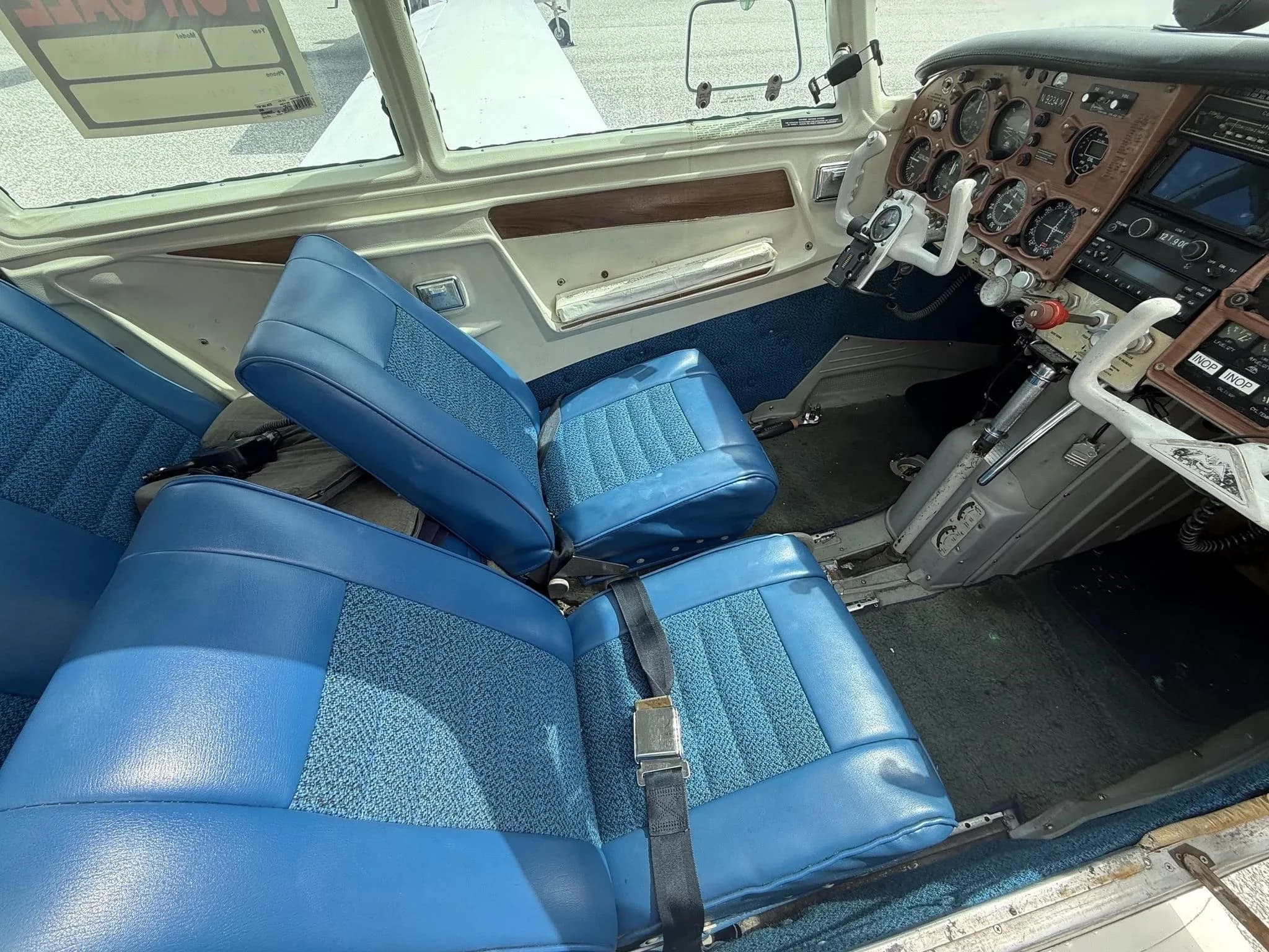 The blue interior seats of the aircraft cabin with a partial view of the cockpit and instrument panel.