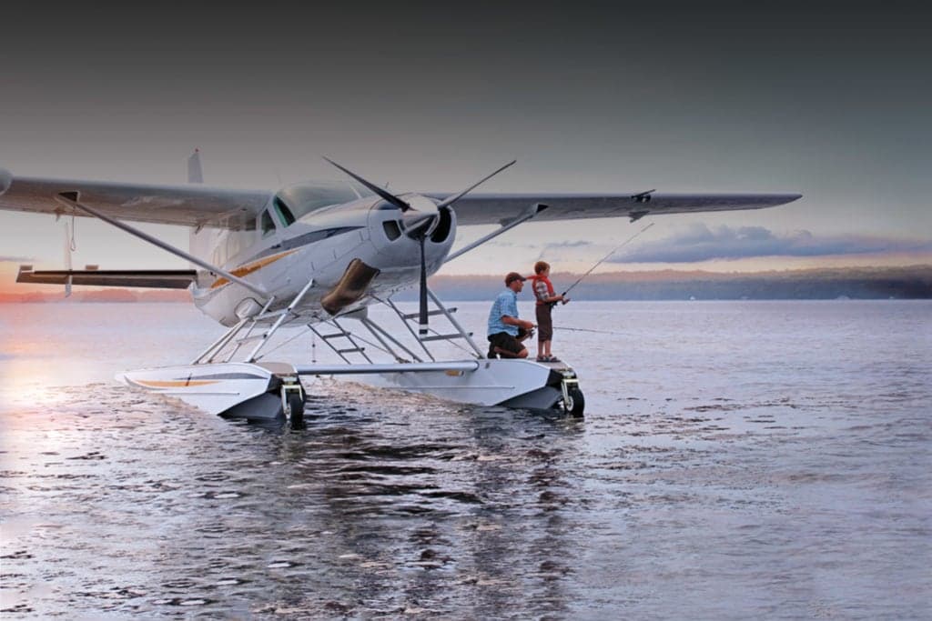 A Cessna Caravan seaplane with people fishing off the floats.