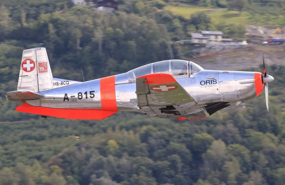 Pilatus PC-7 in flight with orange and silver paint scheme.