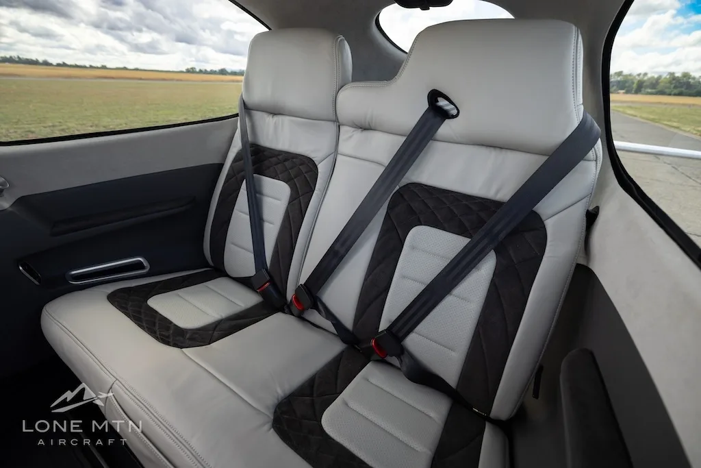 The light gray and black rear passenger seats of a small aircraft cabin, viewed from a slightly different angle.