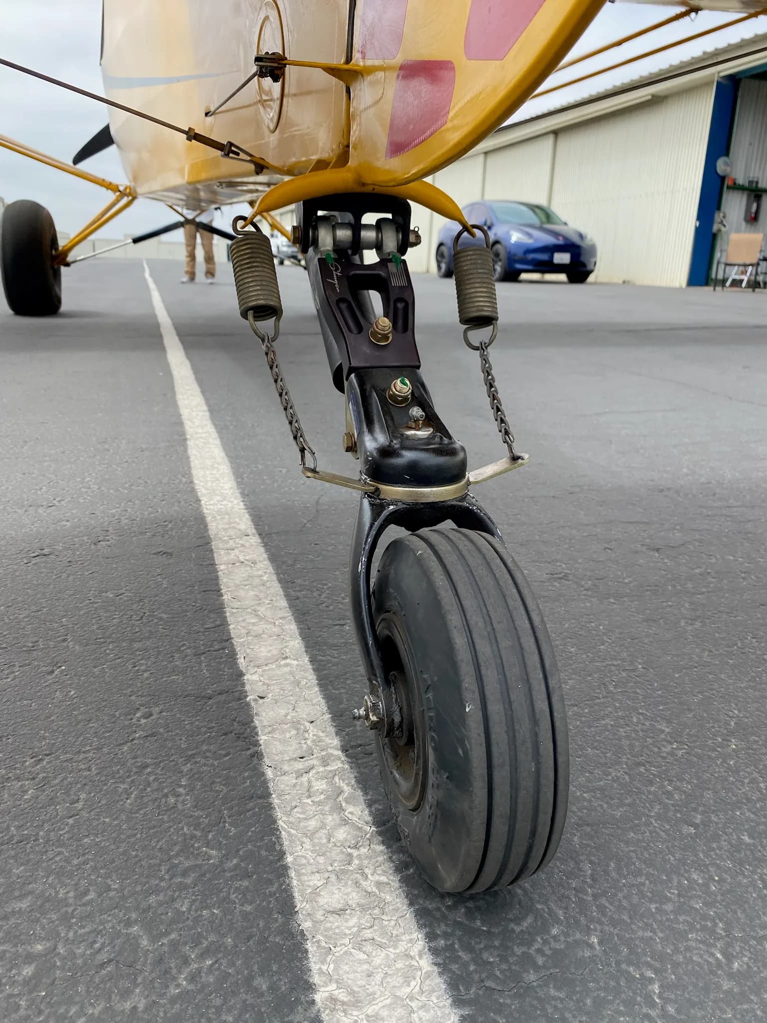 Close up of the landing gear and tire of a yellow Carbon Cub aircraft.