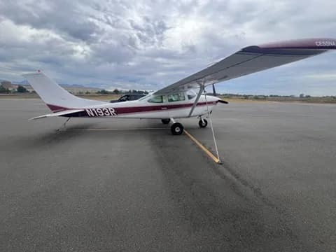 A white and maroon Cessna 182 aircraft (N193R) is parked on an asphalt tarmac under a cloudy sky.