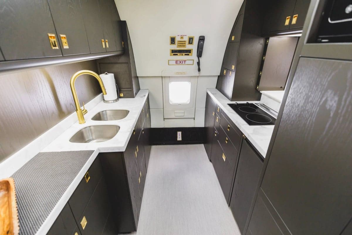 View of the aircraft's galley with stainless steel sinks and dark wood cabinets.