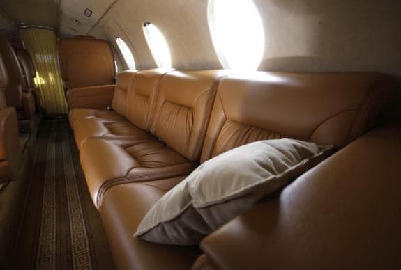 Interior view of the aircraft cabin with a leather couch and pillow.