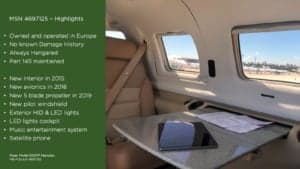 Aircraft interior with seats, table, and window.