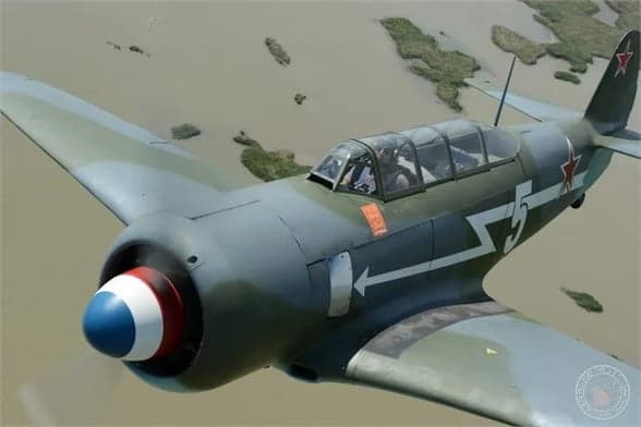 A Lavochkin La-9 in flight with a gray and green paint scheme and a red star on the tail.