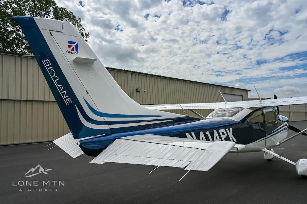 A rear quarter view of the blue and white Cessna Skylane N414PK, showing the tail with "Skylane" and "Cessna" logos.