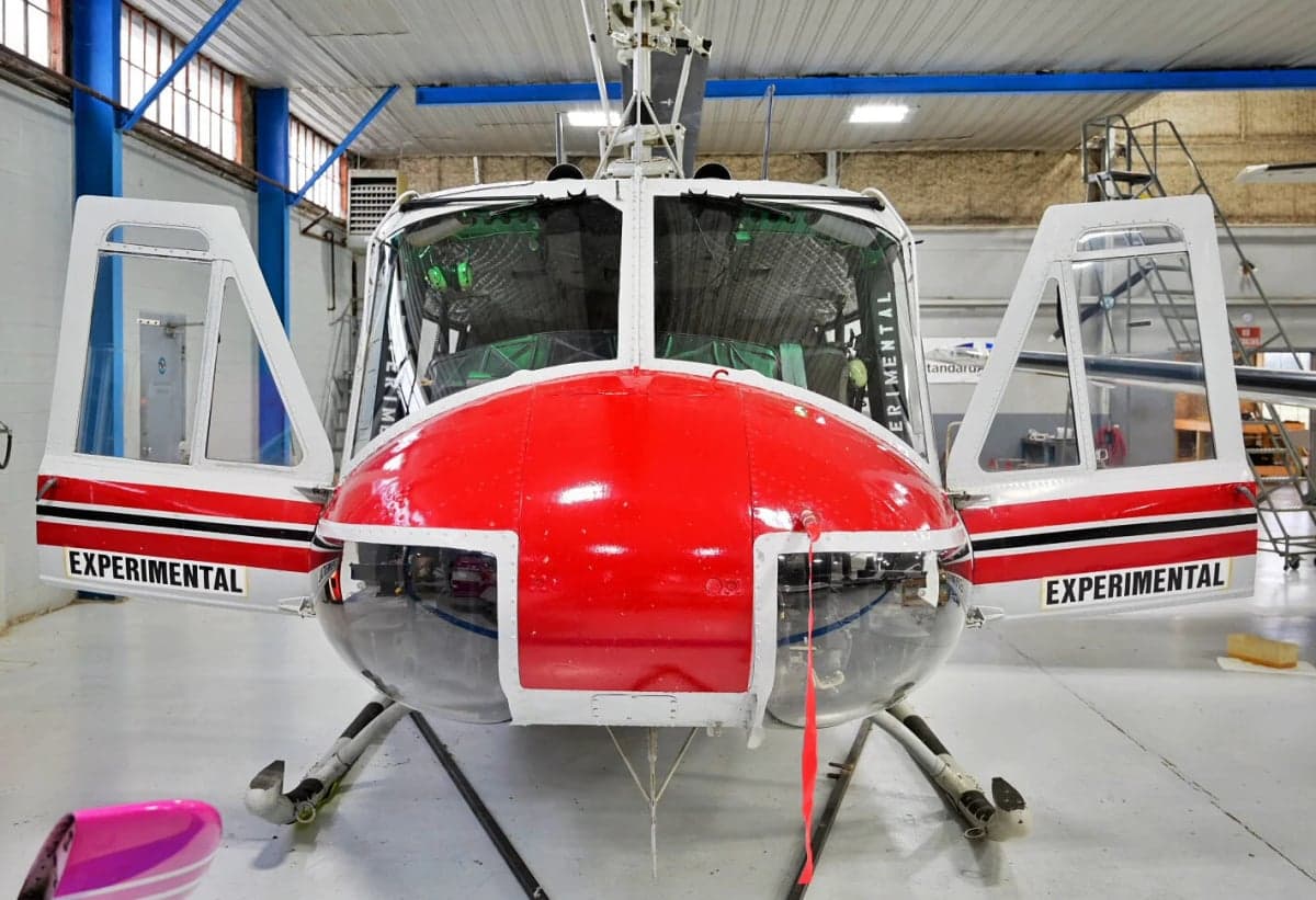 Front view of the N857SD helicopter with open doors in a hangar.