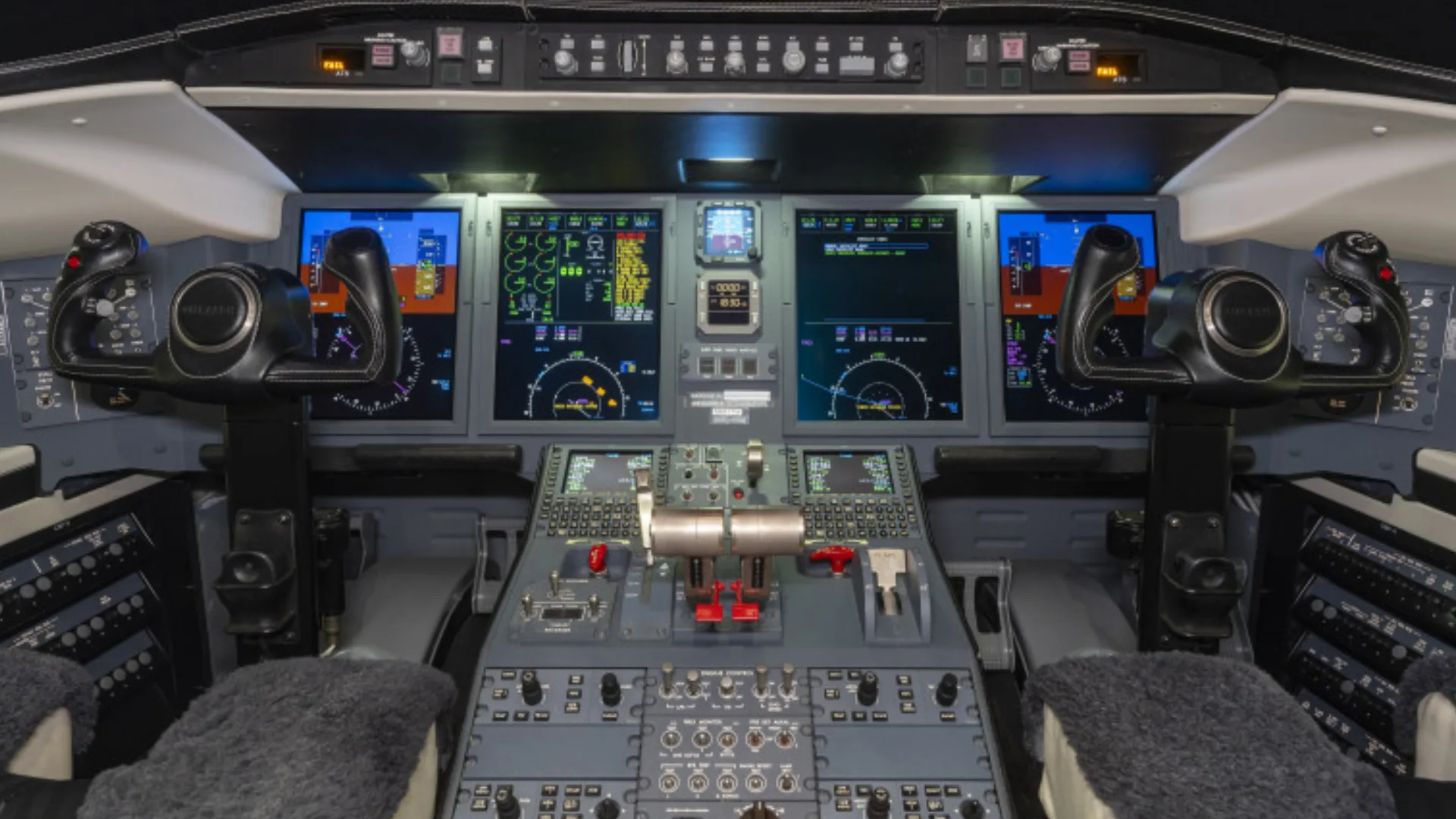 The modern cockpit of a Bombardier Challenger 605 business jet, featuring multiple digital displays and controls.